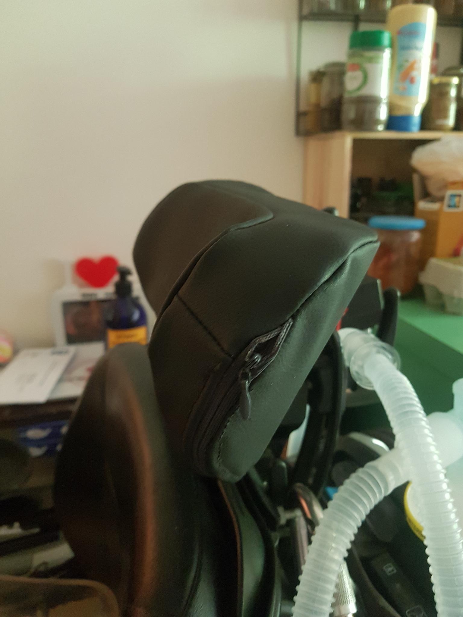 la housse d'apui tête sur un appui tête vue de coté. on y vois l'extrémité de la fermeture éclair qui cours sur le bas arriére de la housse