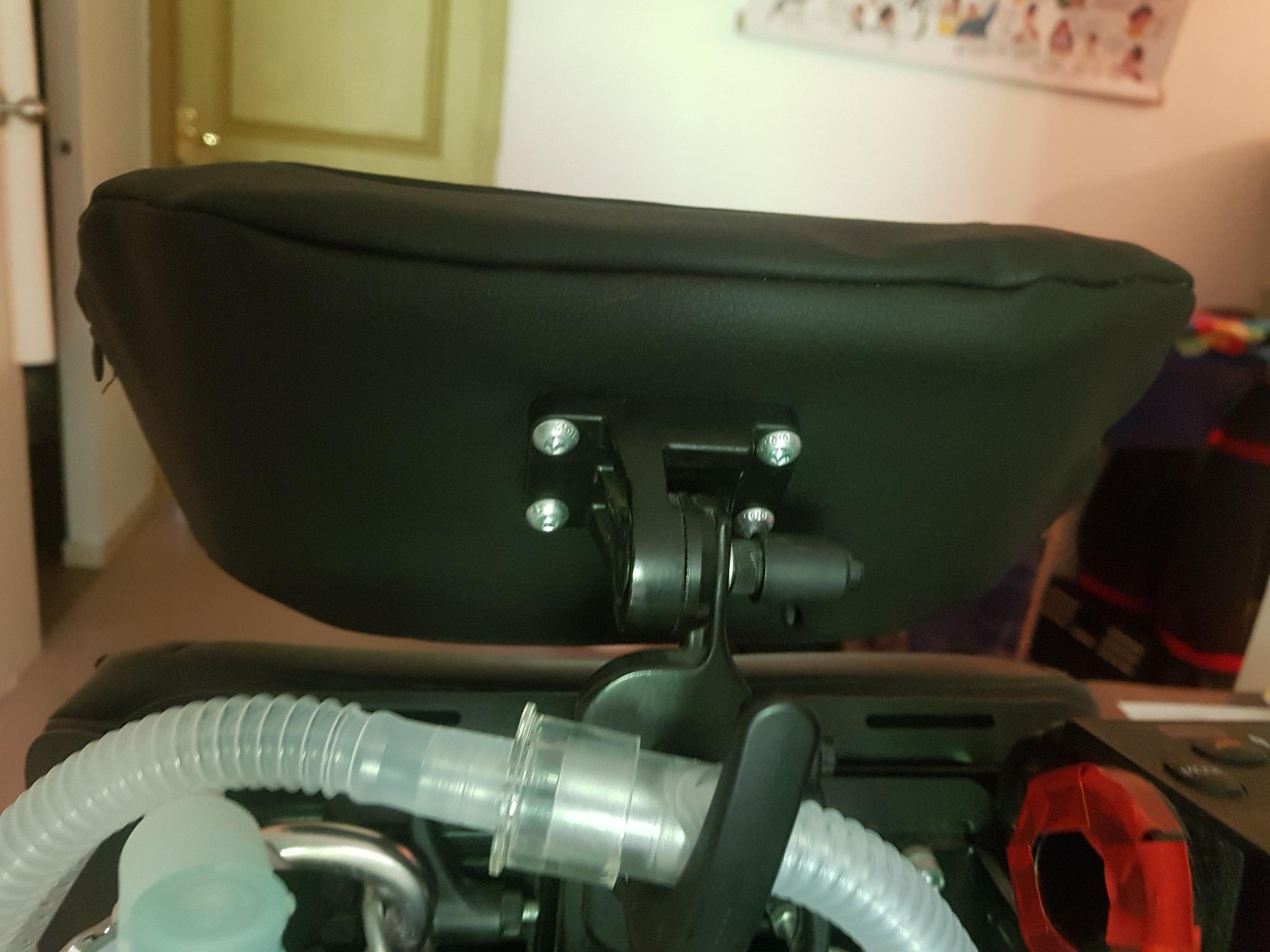 la housse d'appui tête sur un appui tête vue de derriére. l'appui tête est directement vissé sur son support et le tissus est un similicuir noir.