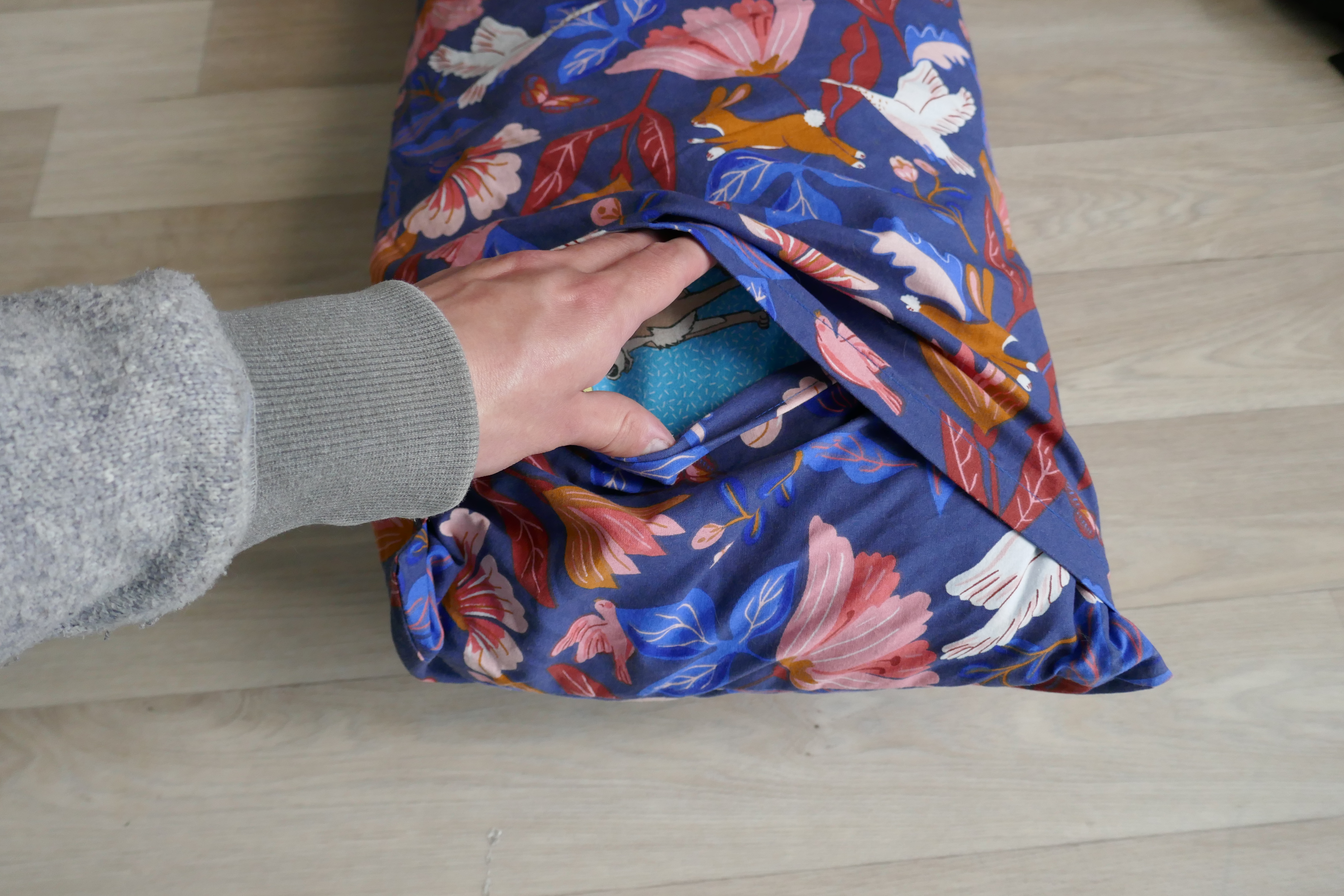 L'extrémité du coussin avec une main qui ouvre la housse pour montrer le rabas