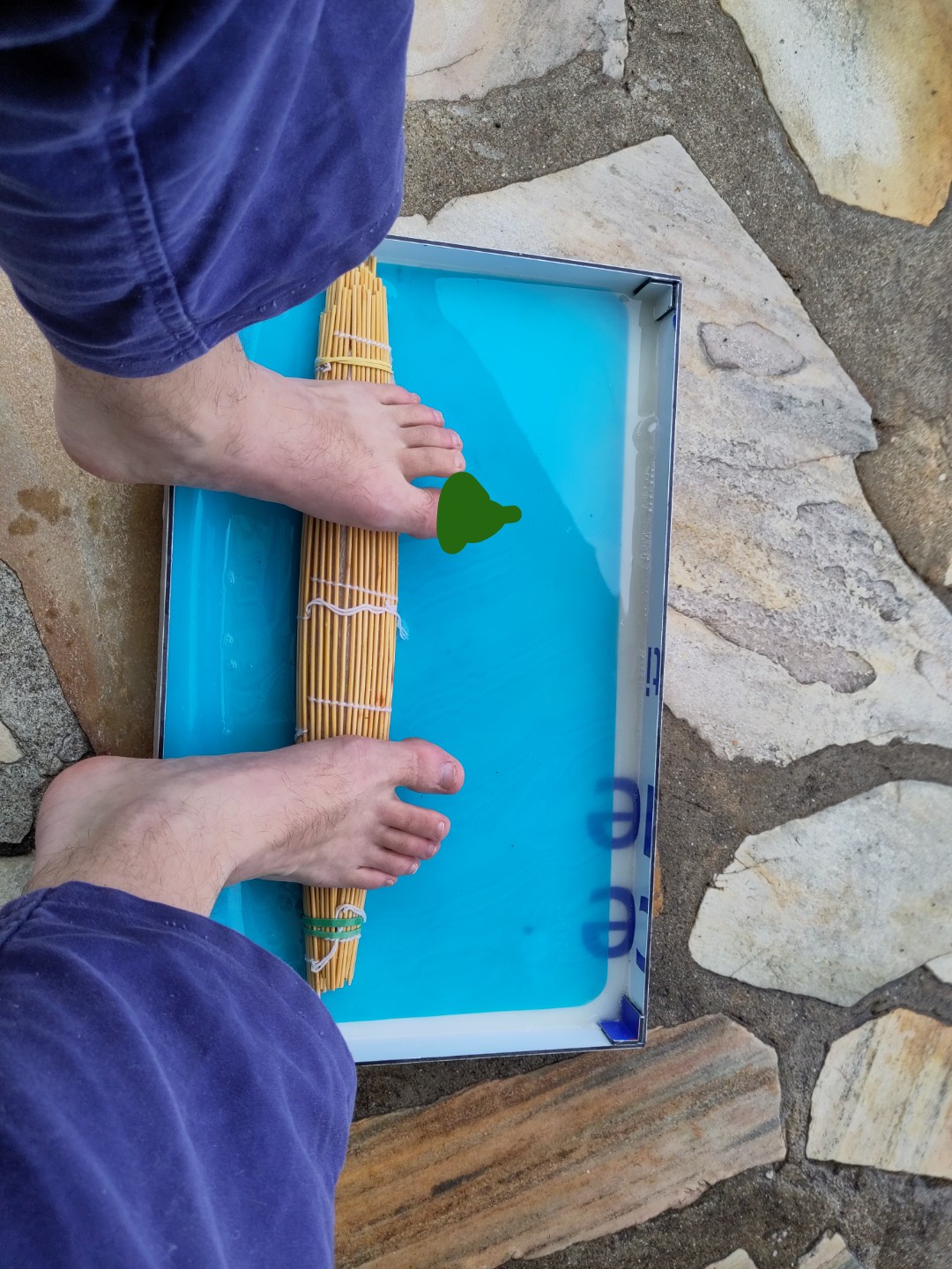 deux pieds nus qui font rouler un rouleau de nappe de bambou dans un plateau. on voit que la position est plutot ergonomique.