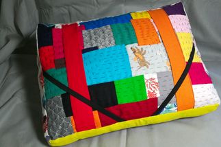 un coussin de lecture en tissus de récup. il est donc bariolé sur le devant en mode patchwork