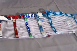 Des poches a savon en éventail sur un fond gris. elles sont composé d'un filet blanc avec des bords en tissus coloré.